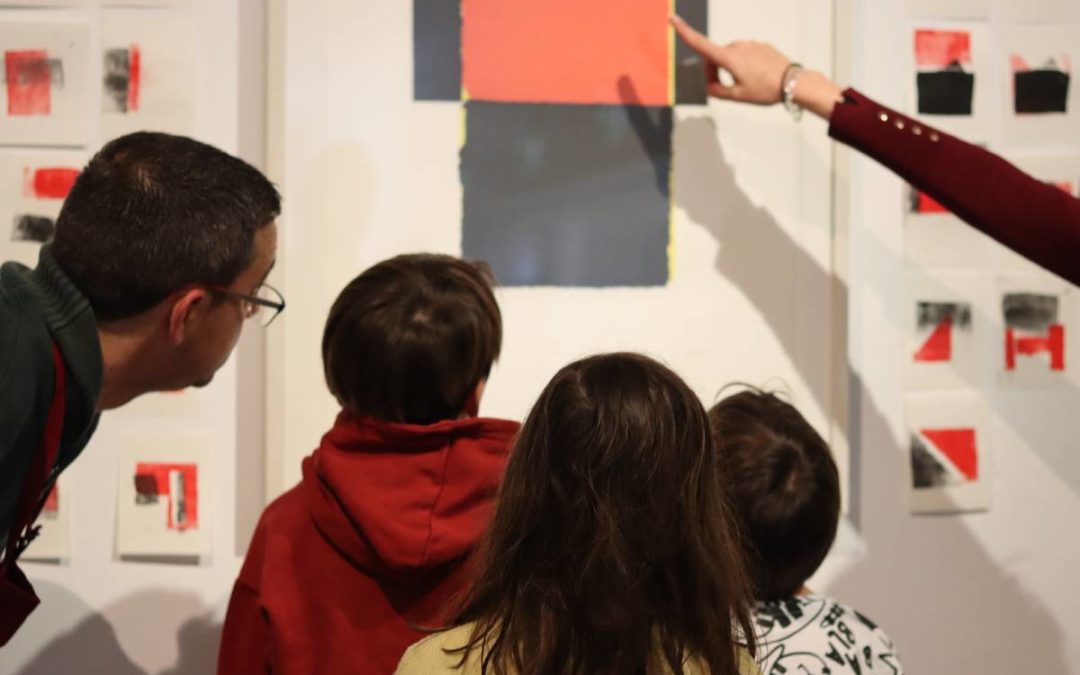 Varios niños y adultos observando una pieza de arte contemporáneo